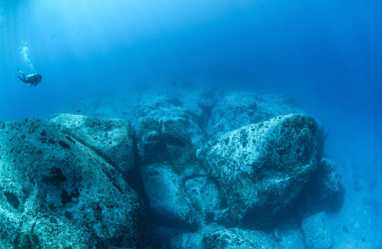 Image of a scuba diver descending onto a granite reef in Seychelles.