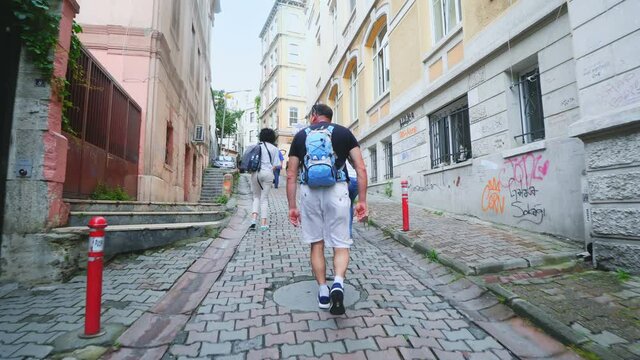 Tourists walk along narrow ancient street toward Galata tower in Istanbul, Turkey