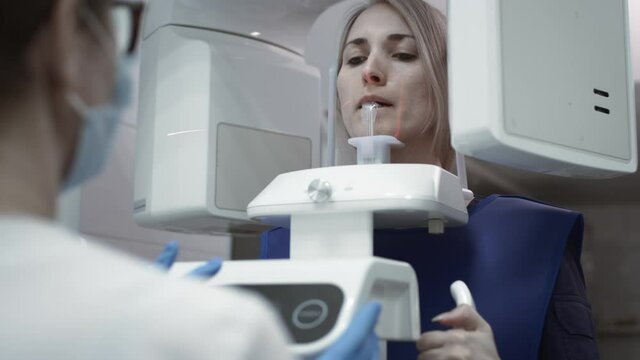 Dental jaw scanning. Patient girl inside a panaromaniac 3d scanner of teeth. Diagnostic equipment orthopantomographic device for teeth, MRI. Creates a 3D model of teeth and gums on a medical monitor