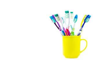 Several old toothbrushes are housed in a yellow plastic tumbler isolated on white background.