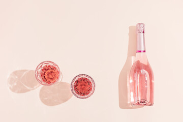 Bottle of rose champagne wine and two glasses with drink in bright sunlight. Summer vacation...