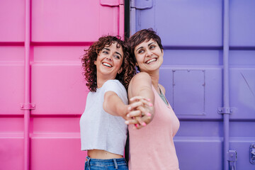 happy lesbian couple holding hands over pink and purple background. Love is love. LGTBI concept