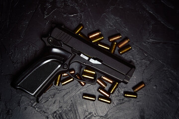 Top view of gun and bullets. Firearms on dark background. Pistol for defense or attack. Concept of crime ammunition and physical evidence. Weapons on concrete table.