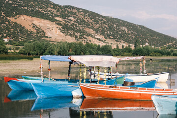 Fototapeta na wymiar Colorful boats on the lake at the foot of the mountain. Boats of people engaged in fishing.