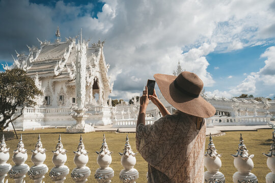 Woman tourist making picture of Wat Rong Khun, known as the White Temple