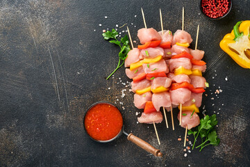Raw shish kebab on wooden board, spices, herbs and vegetables on dark grey background. Barbecue Raw...