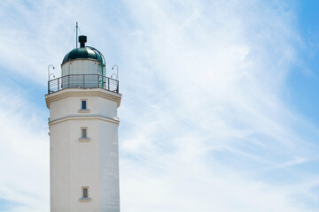 Lighthouse on the background of a sunny sky with clouds. Selective focus. Copy space.