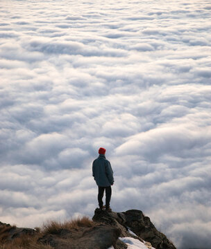 Travel lifestyle view of man on mountain hike above cloud inversion on Roys Peak, near Wanaka, South Island of New Zealand.