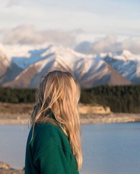Travel lifestyle view of blonde girl in snowy mountains in winter near Mount Cook Cook National Park, on the South Island of New Zealand.