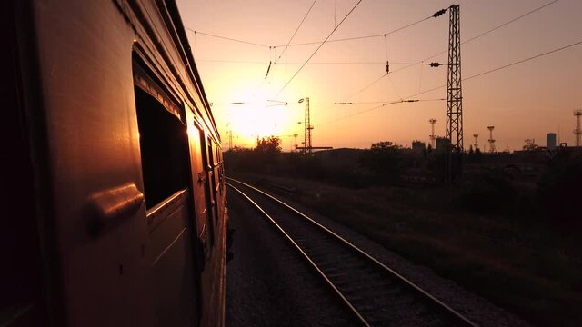 Old train making a turn on sunrise or sunset from passenger window view on a clear summer day