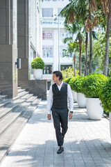 Successful man in formal black suit and sunglasses walking on the street and looking aside.
