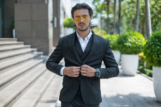 Portrait of handsome young man in black formal suit and yellow sunglasses 