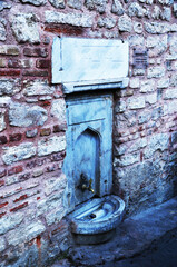 Drinking water tap in a brick wall. Old faucet for water.
