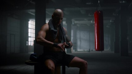 Boxer wrapping hands in boxing tapes. Focused sportsman using punching wraps  - Powered by Adobe