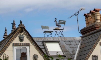 metal cockerel balanced on a metal chair on a roof top