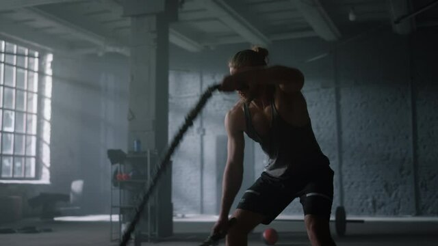 Man training with battle ropes in gym. Athlete doing intensity fitness workout