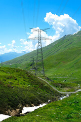 View of electric pylons in nature. Landscape with mountain pastures in the Alps at summer or spring.