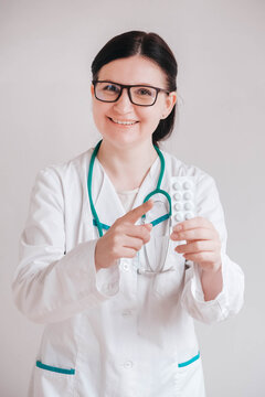 Woman doctor with pills in her hands on a white background. Taking vitamins or medications. Copy, empty space for text