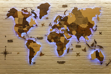 Wooden decorative world map with purple neon backlight on apartment wall. Modern interior design.