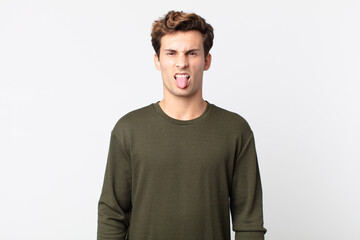 young handsome man feeling disgusted and irritated, sticking tongue out, disliking something nasty...
