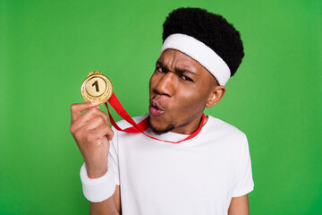 Photo of crazy egocentric sportsman guy showing first place medal wear white t-shirt isolated green...