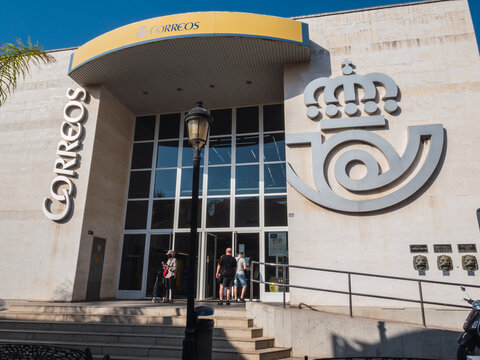 Fuengirola, Spain: July-19-2021. Post office building in summer with people coming and going through the door
