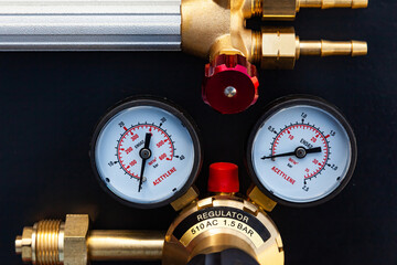Reducer for a gas cylinder with acetylene and part of a gas burner on a black background, close-up.