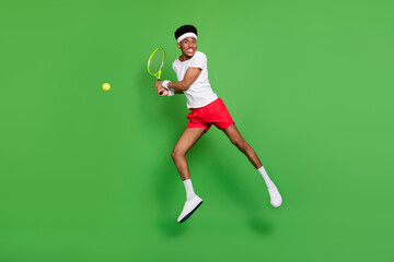 Fototapeta na wymiar Photo of tennis player guy jump hold racquet wear white t-shirt shorts sneakers isolated green color background