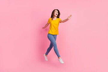 Fototapeta na wymiar Full size photo of funky brunette hair young lady jump wear yellow t-shirt jeans isolated on pink background