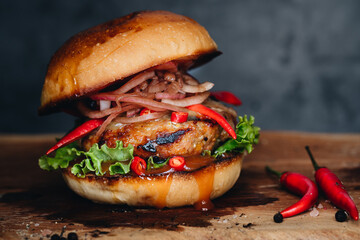 Spicy burger with marinated onions and chilli on wooden board
