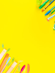 Back to school concept. Colorful writing tools frame on yellow background
