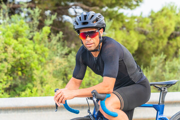 Portrait of professional cyclist resting sitting on the bicycle dressed in black sportswear and...