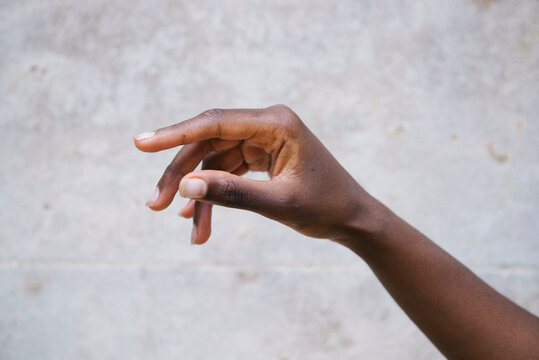 Crop black woman hand against gray wall