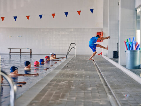 Water aerobics instructor and group of people exercising in pool