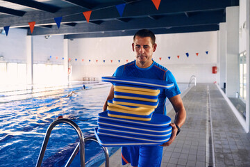 Male swimming coach with kickboards in pool