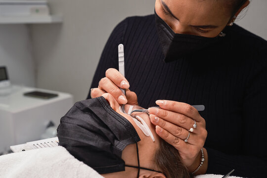 Cosmetologist doing eyelash extension procedure in beauty center