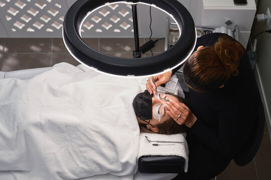 Cosmetologist doing eyelash extension procedure in beauty center