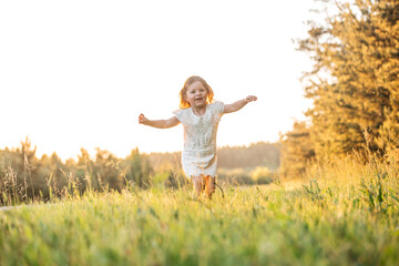 Naklejka na ściany i meble happy baby smiling. little girl running at sunset outdoor