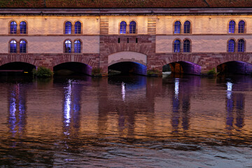 Fototapeta na wymiar STRASBOURG, FRANCE, June 23, 2021 : Barrage Vauban at night. This bridge, weir and defensive work was erected in the 17th century on the Ill river, and named Great Lock.