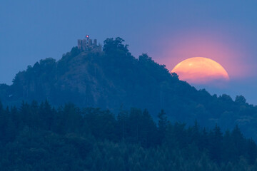 Setting full Moon with the castle Angel Mountain, Czech.