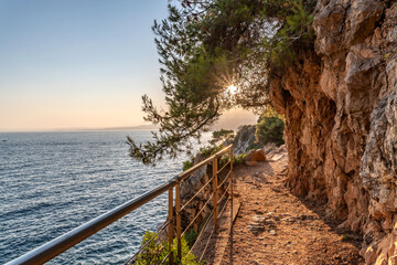 Obraz premium Coucher de soleil sur la Côte d'Azur depuis le Cap Ferrat avec vue mer et pins parasols