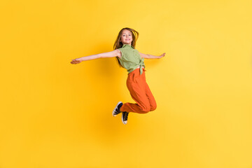 Full length body size photo little girl jumping high carefree overjoyed isolated vibrant yellow color background