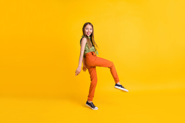 Fototapeta na wymiar Full length body size photo little girl wearing casual clothes careless showing tongue isolated vivid yellow color background
