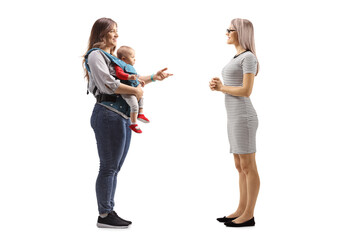 Full length profile shot of a mother with a baby talking to a young woman