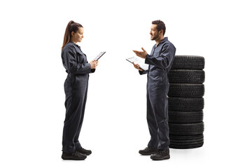 Full length profile shot of a male and female auto mechanic workers having a conversation