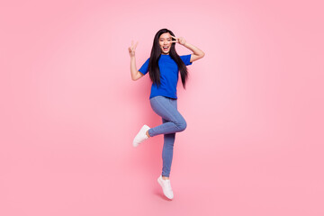 Full length photo of cheerful young woman jump up make v-signs hello smile isolated on pink color background