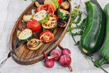 Vegetables kebab. Zucchini, tomatoes and sweet onions on a wooden platter. Grilled organic vegetables. Cooked vegetables and sauce. Food still life. Close-up. Copy space