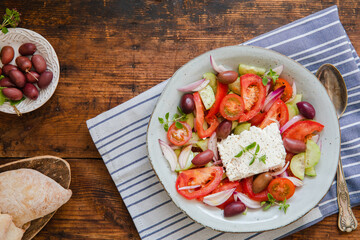 A fresh traditional greek salad horiatiki choriatiki with feta cheese, tomatoes, cucumber, onion and kalamata olives, with fresh homemade bread