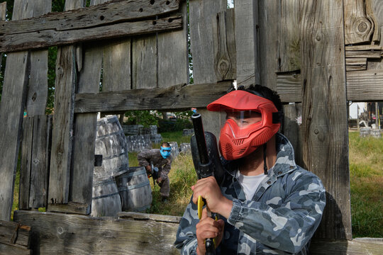 Paintball player hiding behind wooden fence during game