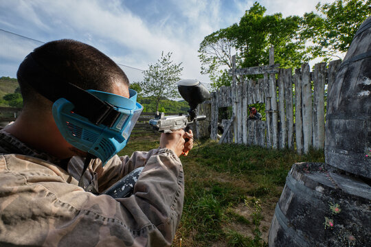 Unrecognizable player aiming at enemy during paintball game
